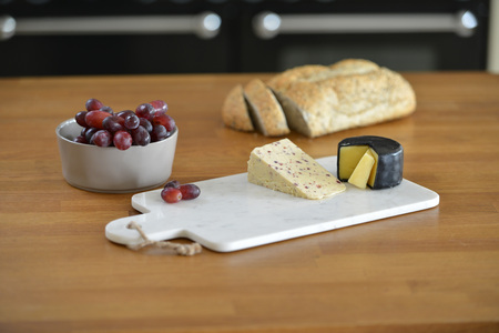 White marble cheese board in a kitchen with cheese and grapesの写真素材