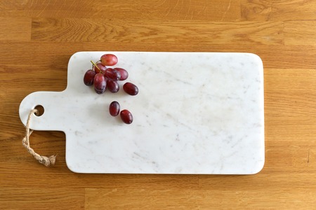 White marble cheese board in a kitchen with cheese and grapesの写真素材