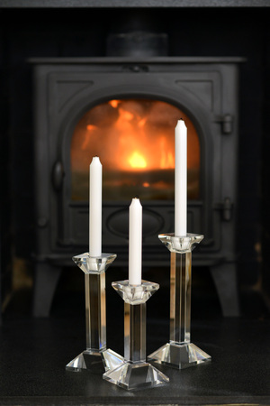 Candles in front of lit wood burning stoveの写真素材