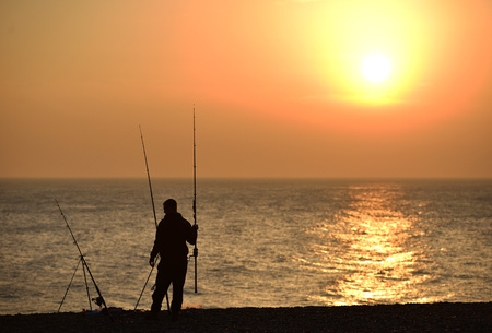 Sea fishing at sunset with three rodsの写真素材