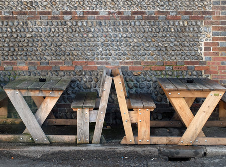 benches and wooden outside tables with flint wallの写真素材