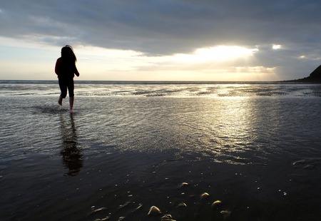 Young girl playing in the water on a sandy beachの写真素材