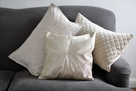 three textured stylish cushions on a grey sofa