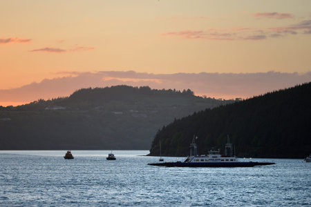 Ferry crossing a wide river at sunset