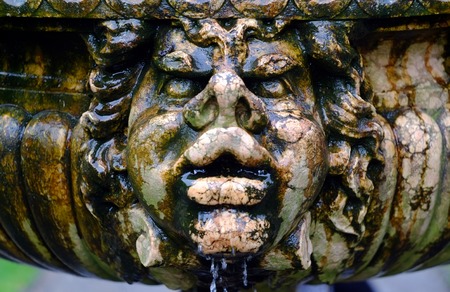 Wet stone face on an old garden fountainの写真素材