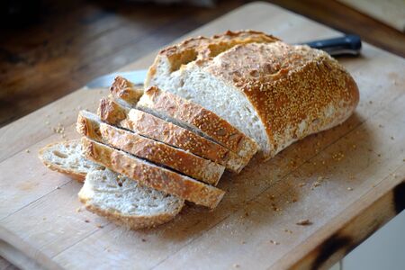 Freshly sliced artisan bread on a wooden board.の写真素材