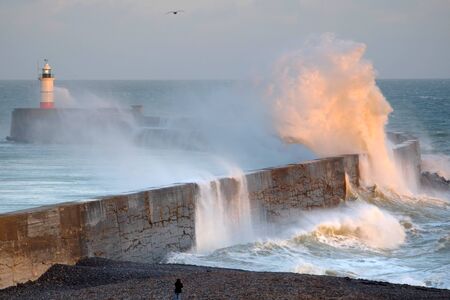 Waves crashing over a harbour wall in Newhaven, UKの写真素材
