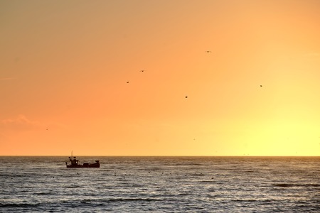 Fishing boat on a calm sea at sunsetの写真素材