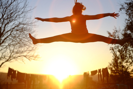 Girl jumping on a trampoline at sunsetの写真素材