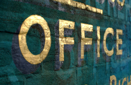 Office sign in gold leaf on a painted brick backgroundの写真素材