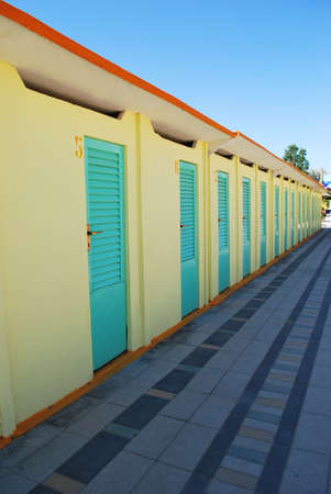 Perspective row of turquoise and yellow beach huts, Rimini, Italyの写真素材
