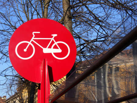 Red and white parking bicycle sign on blue sky and treesの写真素材