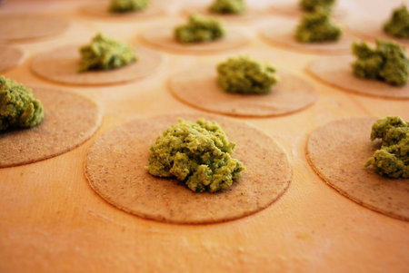 Homemade pasta called ravioli filled with fine herbs and tofu leaning on a wooden countertop