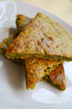 Slices of homemade vegetarian chickpeas cake with herbs in a white dishの写真素材