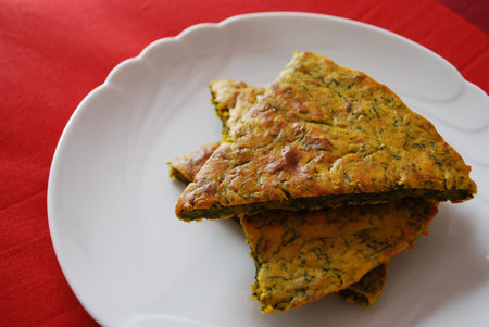Slices of homemade vegetarian chickpeas cake with herbs in a white dish