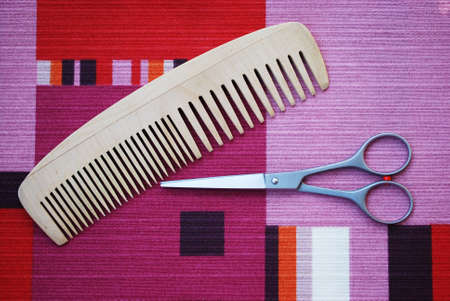 Professional scissors and wooden comb on colorful backgroundの写真素材