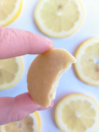 Woman's hand holding a slice of lemon on a white background.の写真素材