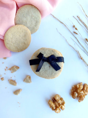 Homemade cookies with a black ribbon and walnuts on a white backgroundの写真素材