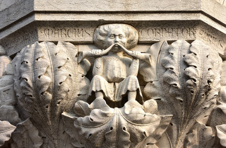 Medieval relief from Doge' Palace in Saint Mark Square with a man blowing into two horns among luxuriant plants symbolizes the month of March and springのeditorial素材
