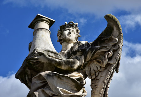Detail of an angel marble statue holding a column at the top of Sant'Angelo Bridge baroque balustrade.の写真素材