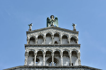Detail from the beautiful romanesque facade of San Michele in Foro church with its typical loggia,  intarsia and a statue of Saint Michael Archangel right in the historic center of Luccaの写真素材