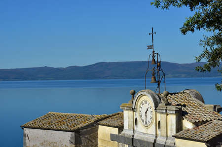 Lake Bracciano viewed from Anguillara Sabazia medieval walls with ancient clockの写真素材