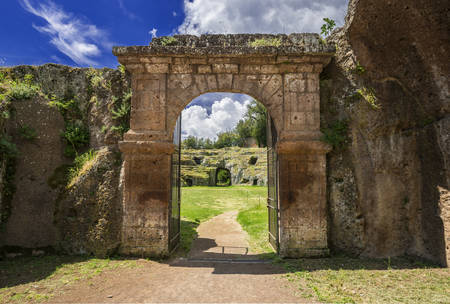 Ancient roman stone amphitheater main gate in the town of Sutri with clouds, near Romeの写真素材