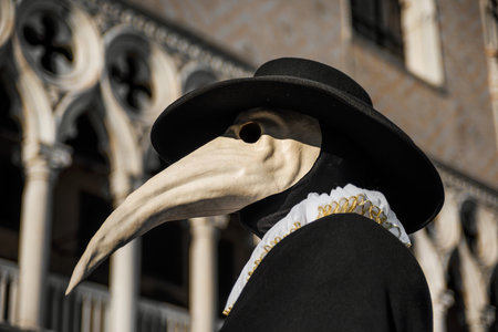 Plague Doctor Mask, traditional venetian costume of Venice Carnival, with Doge Palace gothic decoration in the backgroundのeditorial素材