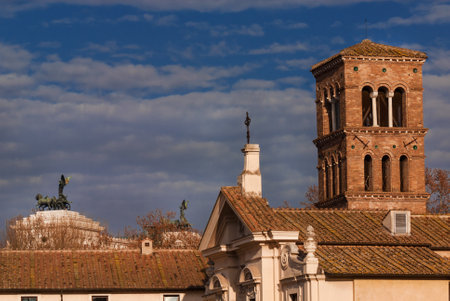 Winter view of St. Bartholomew on the Island medieval bell tower with Vittoriano Moument in the background with clouds, in the historic center of Romeのeditorial素材