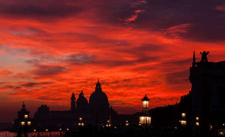 Red blood sky sunset over Venice Lagoon with Salute Basilica domes Saint Mark Lion and lampsの写真素材
