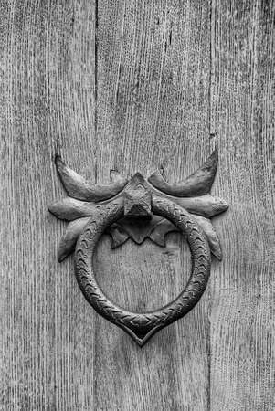 Old wrought iron door clapper on wooden door (Black and White)の写真素材