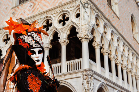 Venice, Italy, February 26, 2017: Carnival in Venice. Beautiful venetian mask with fan, in front of Doge Palaceのeditorial素材