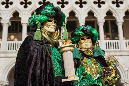Venice, Italy, February 10, 2018: Carnival in Venice. Two beautiful Venetian masks with Saint Mark Lion in front of Doge Palaceのeditorial素材