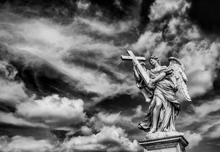 Angel holding the Holy Cross with heavenly sky and copy space. A 17th centuty baroque masterpiece at the top of Sant'Angelo Bridge in the center of Rome (Black and White)のeditorial素材