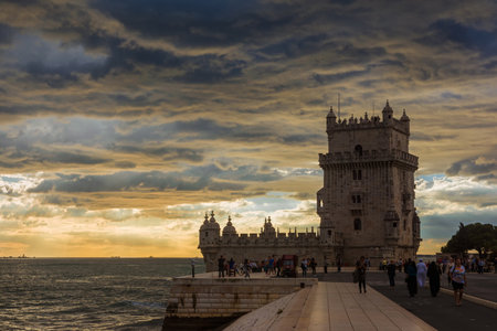 Tourists visit the famous Belem Tower near Lisbon with beautiful sunset over Atlantic Oceanのeditorial素材