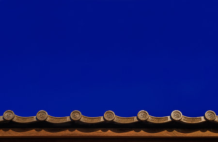 Japanese traditional grey roof tile with old spiral motif and blue sky above as background (with...