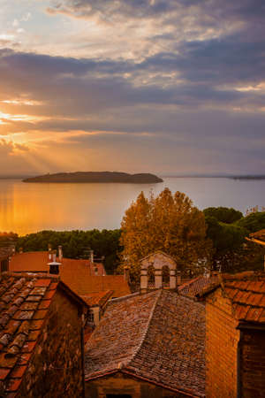 Beautiful sunset over Passignano historic center with Isola Maggiore (Greater Island) in Lake Trasimenoの写真素材