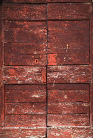 Old red wooden door with worn varnish as backgroundの写真素材