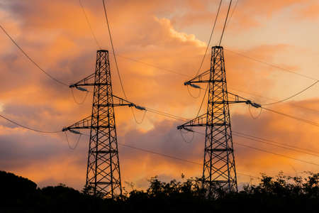 Industrial impact on natural environment. Transmission towers or electricity pylons against beautiful sunset cloudsの写真素材