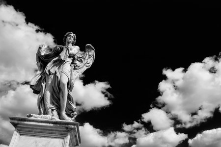 Angel statue holding the garment and dice of Jesus Passion with heavenly clouds. A 17th century baroque masterpiece at the top of Sant'Angelo Bridge in the center of Rome (Black and White with copy space)の写真素材