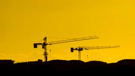 Construction industry and development. Crane at work against golden sunset skyの写真素材