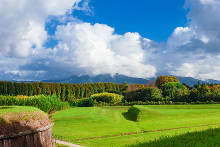The Walls of Lucca public park near St Croce Bulwark with Apennine Mountains wrapped in cloudsの写真素材