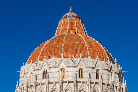 Pisa Baptistery beautiful medieval dome with gothic reliefs and red tilesの写真素材