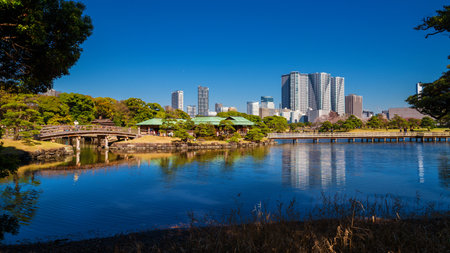 TOKYO, JAPAN - APRIL 4, 2019: Japan between tradition and modernity. Tokyo Hamarikyu Garden with old pavilion and wooden bidge with modern skyscrapers in the backgroundのeditorial素材