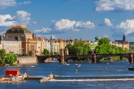 Prague beautiful rivefront on River Vltava with the National Theatre, the Legion Bridge, the Slovansky Island and paddle boatsの写真素材