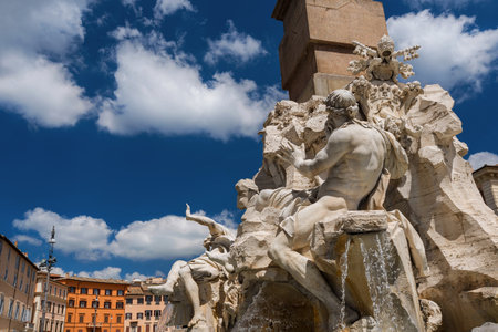 The wonderful Fountain of the Four Rivers in Navona Square, erected in the 17th century, with blue sky and white cloudsの写真素材