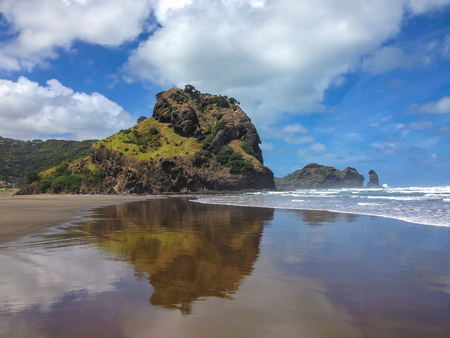 piha beach reflected in the sea with azure sky and cloudsの写真素材