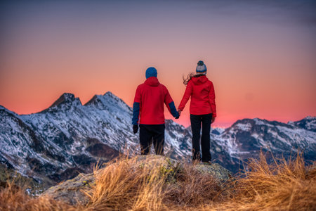 couple of people watch the sunset from a mountainの写真素材