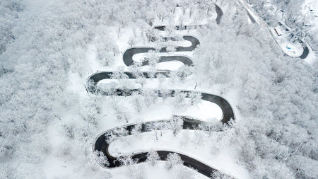 mountain road with many curves through snowy forest in switzerland