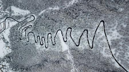 mountain road with many curves through snowy forest in switzerlandの写真素材